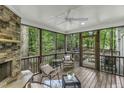 Inviting screened porch featuring a stone fireplace, ceiling fan, and comfortable seating for outdoor relaxation at 2325 Old Oak Pl, Hillsborough, NC 27278