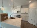 Modern kitchen with white cabinets, granite countertops, stainless steel appliances, and stylish pendant lighting at 285 Gregory Village Dr, Lillington, NC 27546