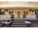Charming yellow home with inviting covered porch, brick columns, potted plants, and a brick staircase at 311 N Gregson St, Durham, NC 27701