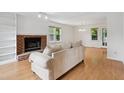Bright living room with brick fireplace, wood floors, and large windows providing natural light at 3405 E Jameson Rd, Raleigh, NC 27604