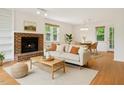 Cozy living room with a brick fireplace, large windows, comfortable seating, and an adjacent dining area at 3405 E Jameson Rd, Raleigh, NC 27604