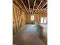 An unfinished living room shows exposed beams, a window, wiring, and a door frame leading to the outside at 432 Golden Dragonfly St, Wake Forest, NC 27587