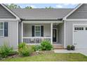 Charming front porch with black seating and landscaping, number 50 over the door, and a garage at 50 Harriet Gentry Ln, Timberlake, NC 27583