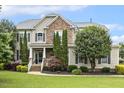 Stunning two-story home showcasing stone facade, manicured landscaping, and a welcoming front porch at 5516 Colonial Oaks Dr, Apex, NC 27539