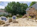 Stone patio with an outdoor fireplace, seating, mature landscaping, and a view of the backyard at 8913 Walking Stick Trl, Raleigh, NC 27615