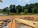 Future backyard backs up to lush green space near lake with mature trees. Construction materials are visible at 1011 Coldspring Circle, Durham, NC 27705