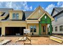 New construction home featuring yellow siding, a dark roof, a front entry porch and an attached two-car garage at 1027 Coldspring Circle, Durham, NC 27705