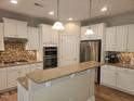 Spacious kitchen featuring white cabinets, stainless steel appliances, an island with pendant lighting, and granite countertops at 112 Briarfield Dr, Apex, NC 27502