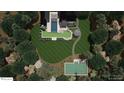 An aerial view of the backyard featuring a pool, sport court, patio, and lush landscaping surrounded by mature trees at 1132 Wimbleton Dr, Raleigh, NC 27609