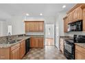 Functional kitchen with oak cabinets, granite countertops, tiled floor, and modern black appliances at 188 Worthington Ct, Clayton, NC 27527