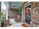Cozy front porch with rocking chairs, brick columns, and a view of the stained wood front door at 2100 Della Ct, Apex, NC 27502
