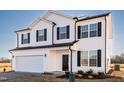 Attractive two-story home with white siding, dark shutters, well-manicured landscaping, and an attached two-car garage at 285 Johnson Ridge Way, Four Oaks, NC 27524