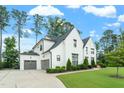 Elegant white brick home featuring a three-car garage, manicured lawn, and beautiful architectural details at 3160 Mantle Ridge Dr, Apex, NC 27502