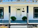 Close-up of the front porch with a white door, potted plants, and gray painted deck at 602 Dexter St, Rocky Mount, NC 27803