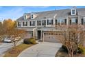 View of townhome with a spacious two-car garage, professional landscaping, and well-maintained grounds at 635 Grace Hodge Dr, Cary, NC 27519