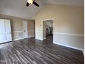 Bright and airy living room featuring vaulted ceiling and modern, dark-wood-look floors, leading into the kitchen at 803 Flat Rock Church Rd, Louisburg, NC 27549