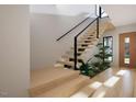 Contemporary floating staircase with natural wood, black railing, and lush greenery beside it at 10 Gambel Dr, Youngsville, NC 27596