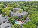 An aerial view of the condominiums with a swimming pool, mature trees, a parking lot, and rooftops at 1061 Wirewood Dr # 303, Raleigh, NC 27605
