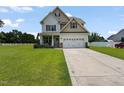 Charming two-story home with a well-manicured lawn and a two-car garage on a sunny day at 15 Scuppernong Ln, Lillington, NC 27546
