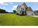 Charming two-story home featuring a manicured lawn and a convenient two-car garage at 15 Scuppernong Ln, Lillington, NC 27546
