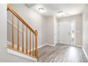 Bright foyer with wood-look floors, a white front door, and a staircase with wooden railing at 1527 Haywards Heath Ln, Apex, NC 27502