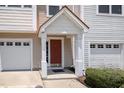 Exterior view of a townhome entrance with a garage, a brick-red door, and a decorative porch roof at 1527 Haywards Heath Ln, Apex, NC 27502