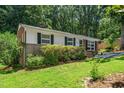 Cozy single-story home with brick and white siding, complemented by a lush green lawn and mature trees for added privacy at 202 Crest Rd, Cary, NC 27513