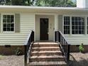 Inviting entryway with brick steps, black railings, and a stylish front door with decorative window panes at 216 Burkwood Ln, Raleigh, NC 27609