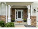 Inviting front porch with stone accents, white columns, decorative lighting, and meticulously maintained landscaping at 347 Country Mill Way, Fuquay Varina, NC 27526