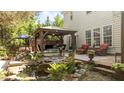 Beautiful backyard oasis with a pond, mature landscaping, a covered patio, and a separate seating area at 648 Long Melford Dr, Rolesville, NC 27571
