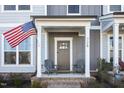 Inviting covered front porch with seating offering a warm welcome to the neutral-tone home at 728 Silo Park Dr, Wake Forest, NC 27587