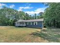 Side view of the home with vinyl siding and white trim surrounded by a lush lawn and mature trees at 1118 Oakridge Duncan Rd, Fuquay Varina, NC 27526