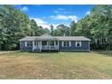 A cozy house with white-trimmed windows and a covered front porch amidst a verdant yard at 1118 Oakridge Duncan Rd, Fuquay Varina, NC 27526