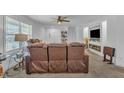 Bright living room featuring a ceiling fan, windows, and plush brown reclining sofas at 1118 Oakridge Duncan Rd, Fuquay Varina, NC 27526