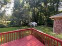 A spacious backyard featuring a wooden deck and a storage shed among mature trees at 143 Cedarwood Dr, Henderson, NC 27536
