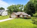 Classic brick home with a large front yard and mature trees on a sunny day at 143 Cedarwood Dr, Henderson, NC 27536