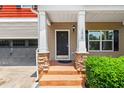 Inviting front porch with stone-based columns, a black front door, and landscaped bushes at 1826 Fillmore Dr, Creedmoor, NC 27522