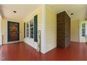 Covered front porch featuring yellow siding, red flooring, a brick support column, and 'Welcome' decor at 2216 Hoskins Rd, Burlington, NC 27215