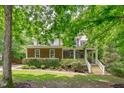 Charming home featuring a manicured lawn, mature trees, and a welcoming front porch with white railings and steps at 297 Curragh Cv, Fuquay Varina, NC 27526
