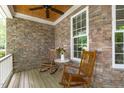Charming front porch featuring exposed brick and two rocking chairs surrounding a small table with flower decorations at 297 Curragh Cv, Fuquay Varina, NC 27526
