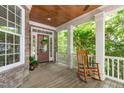 Inviting front porch showcasing stone accents, a wooden rocking chair, and a stylish front door with decorative wreath at 297 Curragh Cv, Fuquay Varina, NC 27526