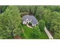 Aerial view of a brick house and a beautiful lawn surrounded by lush, mature trees at 3004 Krogen Ct, Creedmoor, NC 27522
