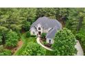 Aerial shot of a brick house with a well-manicured lawn surrounded by lush trees and landscaping at 3004 Krogen Ct, Creedmoor, NC 27522