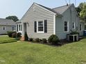 A quaint home featuring gray siding, black shutters, a manicured lawn, and well-maintained landscaping at 306 W Canary St, Dunn, NC 28334