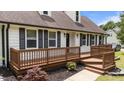 Inviting front porch with a brown wood deck, black shutters, and decorative landscaping at 4259 Old Faison Rd, Knightdale, NC 27545
