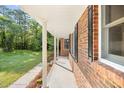 View of the covered front porch with brick columns, offering a shady place to relax at 4964 Stafford Mill Rd, Liberty, NC 27298