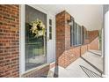 Close-up of the front door with a decorative wreath and a view of the brick facade and covered porch at 4964 Stafford Mill Rd, Liberty, NC 27298