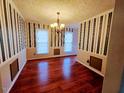 Formal dining room showcasing hardwood floors and decorative striped wallpaper at 5301 Peacenest Dr, Raleigh, NC 27610