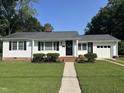 Inviting single-story home with a well-maintained lawn, updated black shutters, and an attached garage at 109 N Watauga Ave, Dunn, NC 28334
