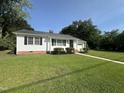 Well-manicured lawn and landscaping accentuates this single-story home with an attached garage on a sunny day at 109 N Watauga Ave, Dunn, NC 28334